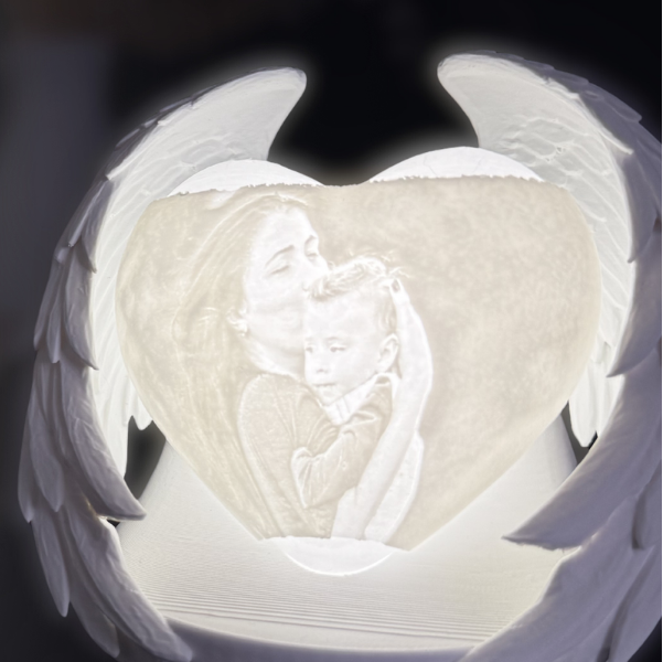 Personalised memorial wings photo light glowing in the dark, featuring a heart-shaped image of a mother kissing a child, framed by angel wings